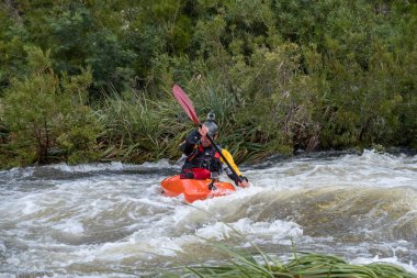Bazı beyaz su rapids Du Toits Kloof yakınındaki Cape Town Güney Afrika nehir üzerinde aracılığıyla doldurma turuncu bir kayık içinde bir kanocu görüntüsünü
