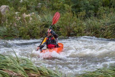 Bazı beyaz su rapids Du Toits Kloof yakınındaki Cape Town Güney Afrika nehir üzerinde aracılığıyla doldurma turuncu bir kayık içinde bir kanocu görüntüsünü