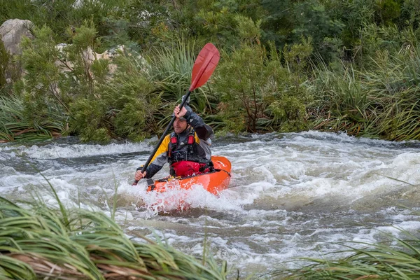 Bazı beyaz su rapids Du Toits Kloof yakınındaki Cape Town Güney Afrika nehir üzerinde aracılığıyla doldurma turuncu bir kayık içinde bir kanocu görüntüsünü