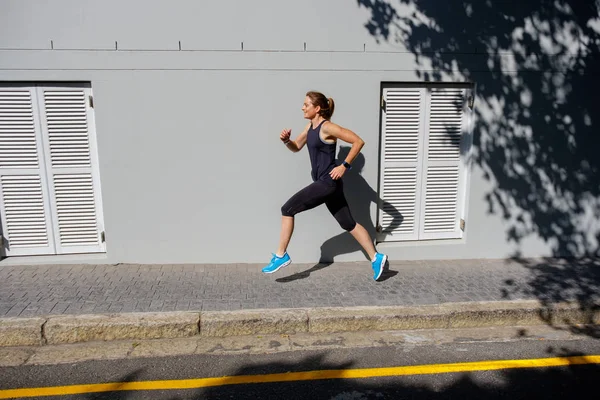 Feminino sprinter correndo ao longo de uma estrada — Fotografia de Stock