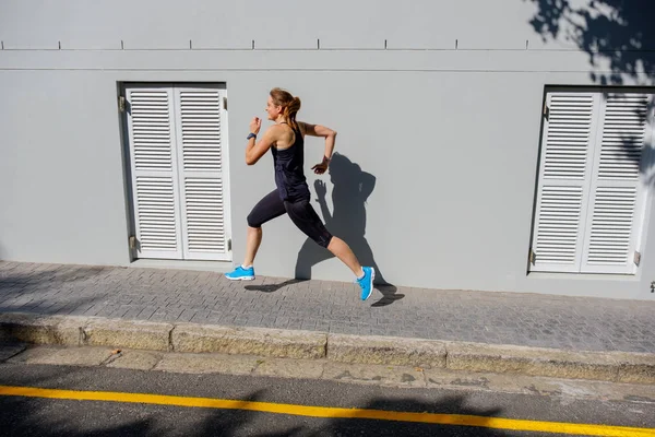 Feminino sprinter correndo ao longo de uma estrada — Fotografia de Stock