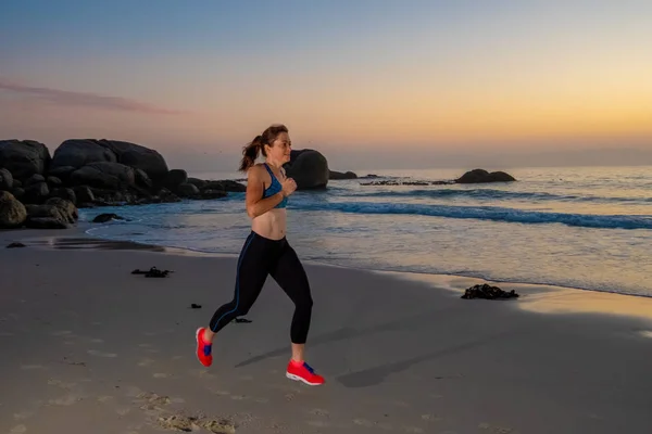 Atleta femminile che corre su una spiaggia — Foto Stock