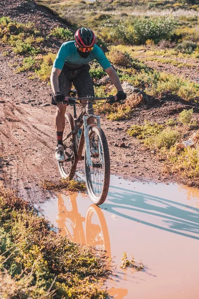 Mountainbiker Met Een Beschermdoekmasker Door Een Modderige Plas — Stockfoto