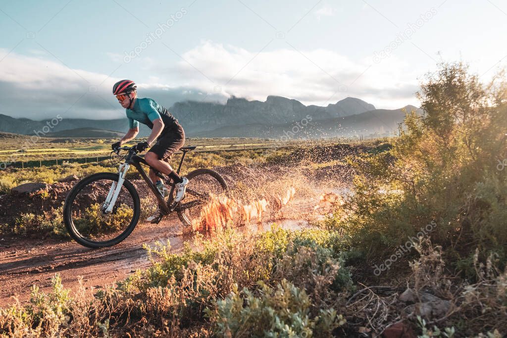 mountain biker racing through a muddy puddle