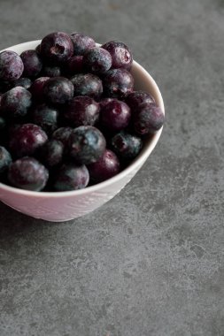 Buzlu ve donmuş yaban mersinleri hala buzla kaplıyken beyaz bir kasede otururlar.