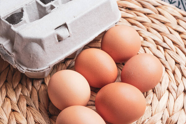 eggs and an egg box on a woven mat background