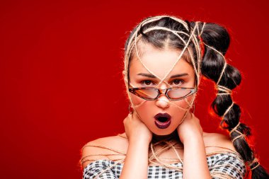 Gözlüklü, rahat saç modeli serin çılgın esmer moda kız portresi. Kadın güzellik makyaj ve saat ile bir iple bağladı. Zaman döngüsü, parlak kırmızı arka plan ile izole kadın 