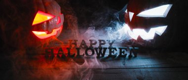 Cadılar Bayramı kavramı. iki parlak turuncu ve mavi ışık ile duman, jack-fener, mutlu Cadılar Bayramı, bir yazıt ile kızgın korkutucu Kabak üzerine ahşap arka plan