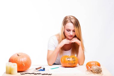 Cadılar Bayramı kavramı, mum ve ip, tatil için hazırlanıyor kabak ile masada oturan kız nasıl fener, komik ve ürkütücü Jack için düşünüyorum. Ya parani ya canini geleneği