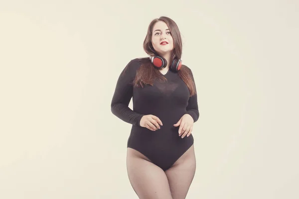 Model plus size with sweet donut, happy girl posing with headpho