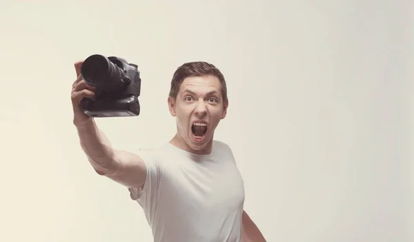 Emocjonalne człowieka z kamerą na białym tle na jasnym tle. Młody ma — Zdjęcie stockowe