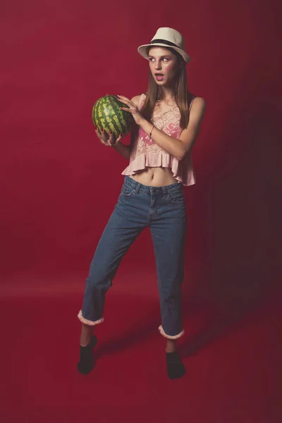 Linda chica con maquillaje rosa, con pantalones vaqueros, sombrero y top, posando — Foto de Stock