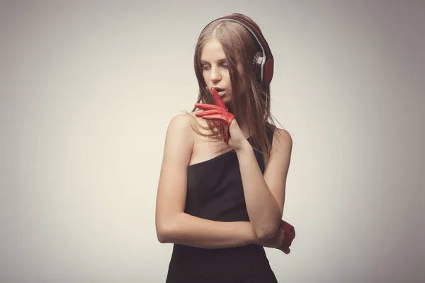 Moda chica bonita escuchando música con auriculares, usando rojo — Foto de Stock