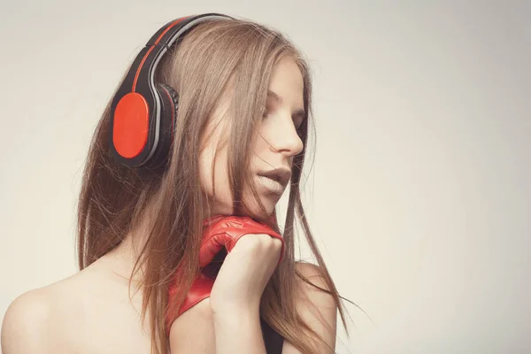 Moda chica bonita escuchando música con auriculares, usando rojo — Foto de Stock