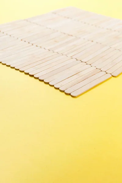 Muitos paus de sorvete de madeira em linha no fundo amarelo — Fotografia de Stock
