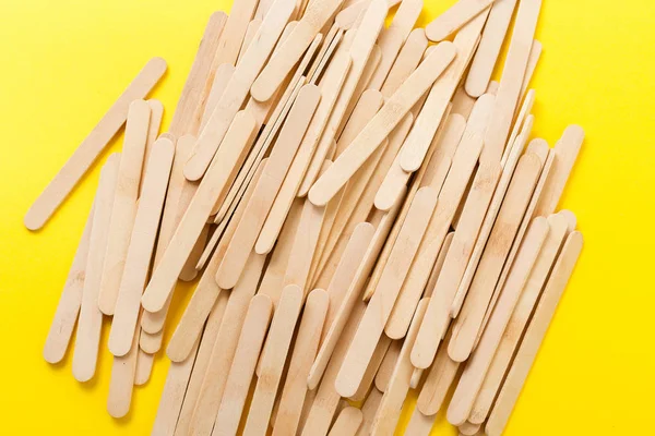 Beaucoup de bâtonnets de crème glacée en bois en tas sur fond jaune — Photo