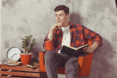 Genç çocuk öğrenci kitaplarla sandalyede oturuyor. Adam öğrenmek istiyor.