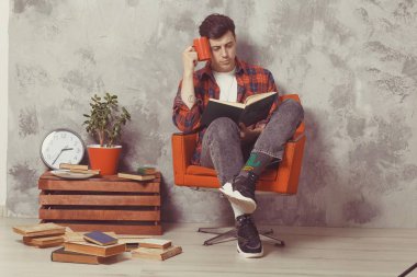 Genç çocuk öğrenci kitaplarla sandalyede oturuyor. Adam öğrenmek istiyor.