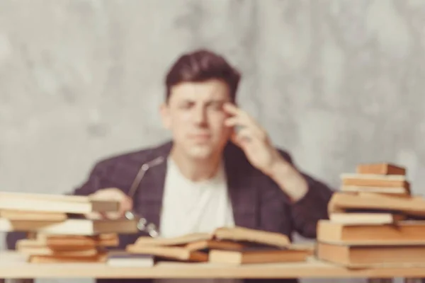 Студент молодого хлопчика сидить біля столу з книгами в окулярах . — стокове фото
