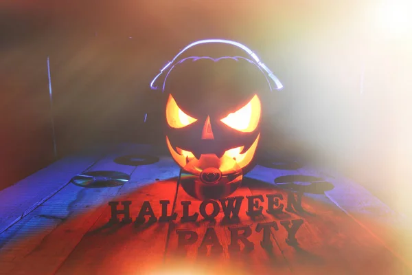 Concept of Halloween. Pumpkin jack Lamp, in headphones with CDs
