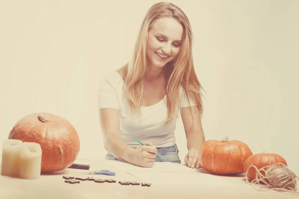 Halloweenský koncept, šťastná dívka sedí u stolu s dýně před — Stock fotografie