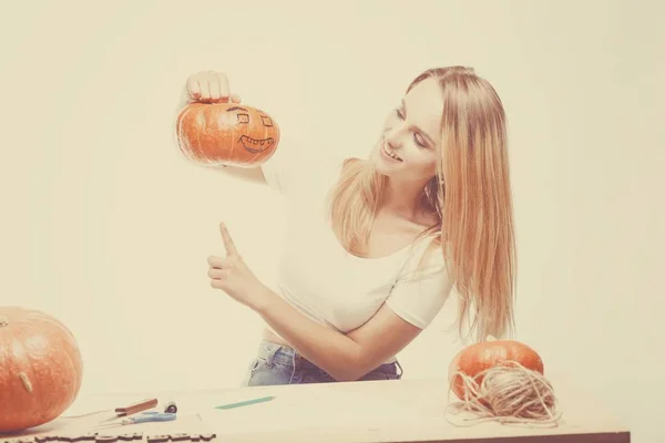 Halloweenský koncept, šťastná dívka sedí u stolu s dýně před — Stock fotografie