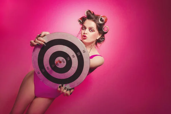 Chica descarada con dardos posando sobre fondo rosa en el cuerpo, con c —  Fotos de Stock