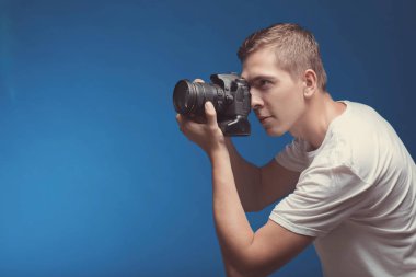 Üzerinde mavi arka plan izole kamera ile gülümseyen adam. Genç adam h