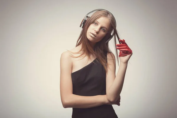 Moda chica bonita escuchando música con auriculares, usando rojo — Foto de Stock