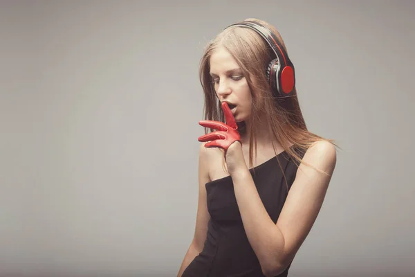 Moda chica bonita escuchando música con auriculares, usando rojo — Foto de Stock