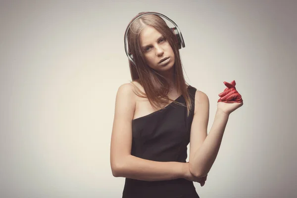 Moda chica bonita escuchando música con auriculares, usando rojo — Foto de Stock