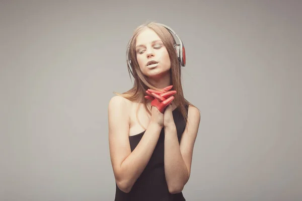 Moda chica bonita escuchando música con auriculares, usando rojo — Foto de Stock