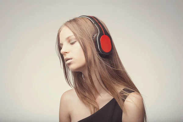 Moda chica bonita escuchando música con auriculares, usando rojo — Foto de Stock