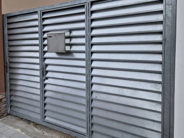 Metal alüminyum çıtçıtlardan yapılmış kapı ve zemin. Kapı çerçevesinde ve çitlerde yatay kirişlerle barut ateşlenmiş boya.