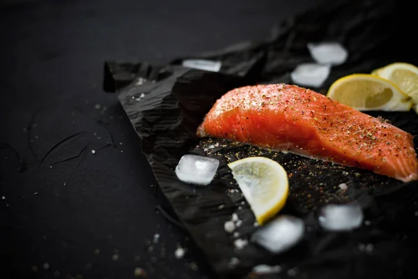 Fresh Salmon with spices on black background with ice and lemon.Eye bird view.Healthy and diet concept.