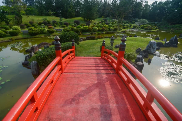 Landscaped grounds and traditional red bridge at the Japanese Garden in Singapore