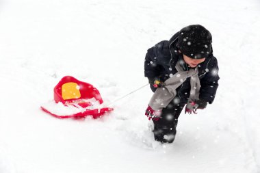 Sevimli küçük komik çocuk kar üzerinde açık havada kar yağışı sırasında eğlenmek. 