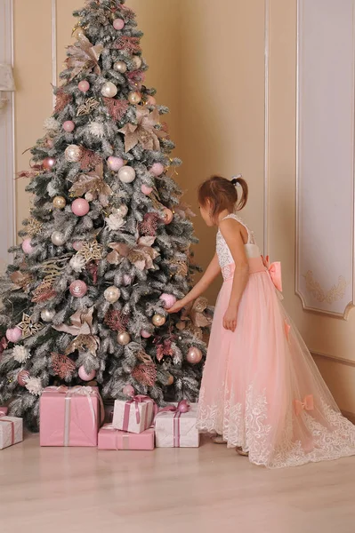 Κορίτσι Στο Ροζ Φόρεμα Εξετάζει Χριστουγεννιάτικο Δέντρο Και Κρέμεται Διακόσμηση — Φωτογραφία Αρχείου