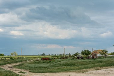 Kasvetli gökyüzünün tarımsal ekipman bir arka plan üzerinde. Kasvetli gök gürültüsü gibi kırsal manzara.