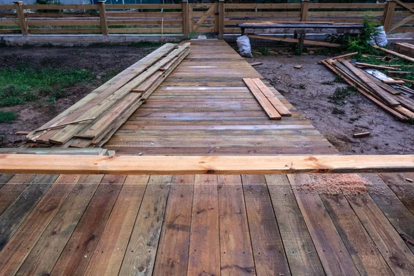A wooden walkway after the rain on the construction of a frame house
