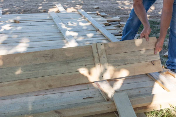 Man building a wooden fence. Workers pick up wooden boards for the fence formwork. Wooden formworks for concrete at construction site.