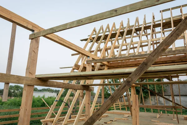 Rafters of the frame of a wooden house at sunset. Construction of a frame house in Ukraine.