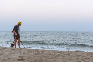 Gün batımı hazine için baktıktan sonra Karadeniz Sahil boyunca hazine avcısı bir metal dedektörü ile yürüyor
