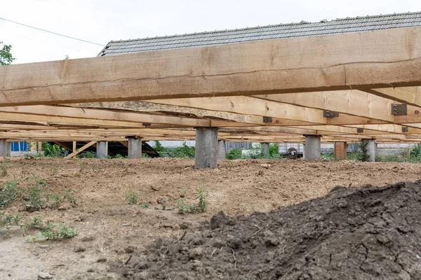 Pile foundation frame house. Piles of concrete and the base of the floor of a wooden house.