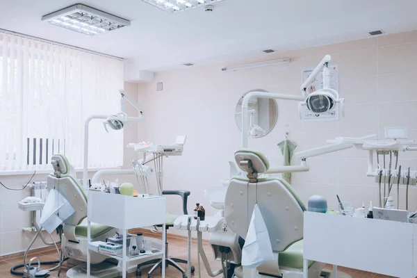 Dental clinic interior design with several dentists chair and tools. Modern dental clinic office with green chairs. Dental office. White tone.