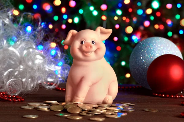 ceramic pig pig with coins on the background of the Christmas tree of balls and white beard of Santa Claus