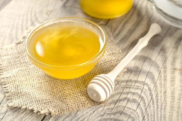 Miel dorada fragante en un frasco de vidrio sobre una mesa de madera —  Fotos de Stock