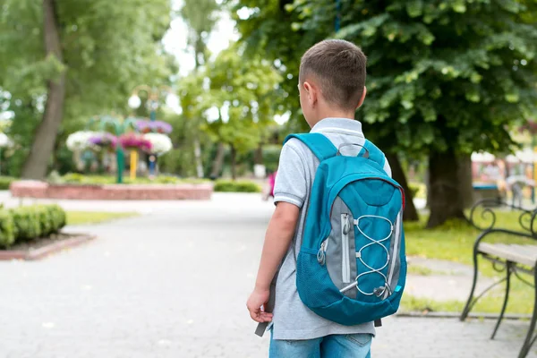 El chico con una mochila camina por el parque Imágenes de stock libres de derechos