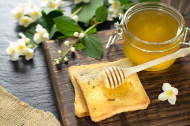 bal ile ahşap kaşık bal bir cam kavanoz yakın bir parça ekmek üzerinde yatıyor