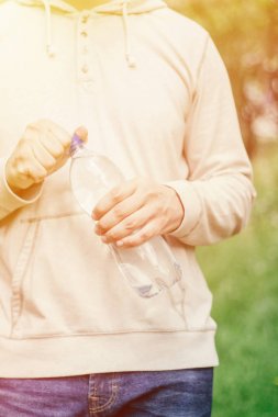 adam hipster doğada su ile plastik bir şişe tutan. sağlıklı yaşam tarzı, yaz, ısı. Parkta yürüyün.